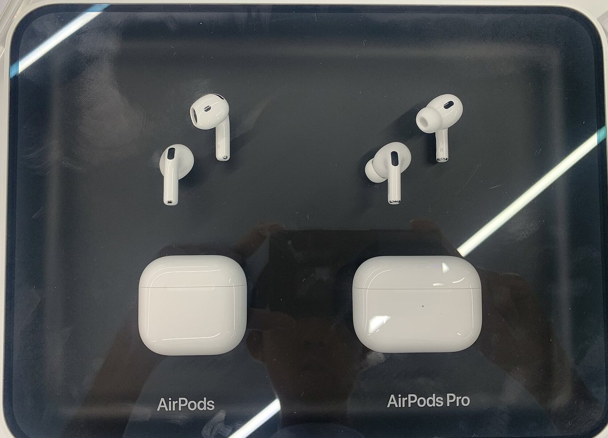 Store display showing open-fit AirPods next to tipped AirPods Pro, illustrating the comfort difference between the two designs