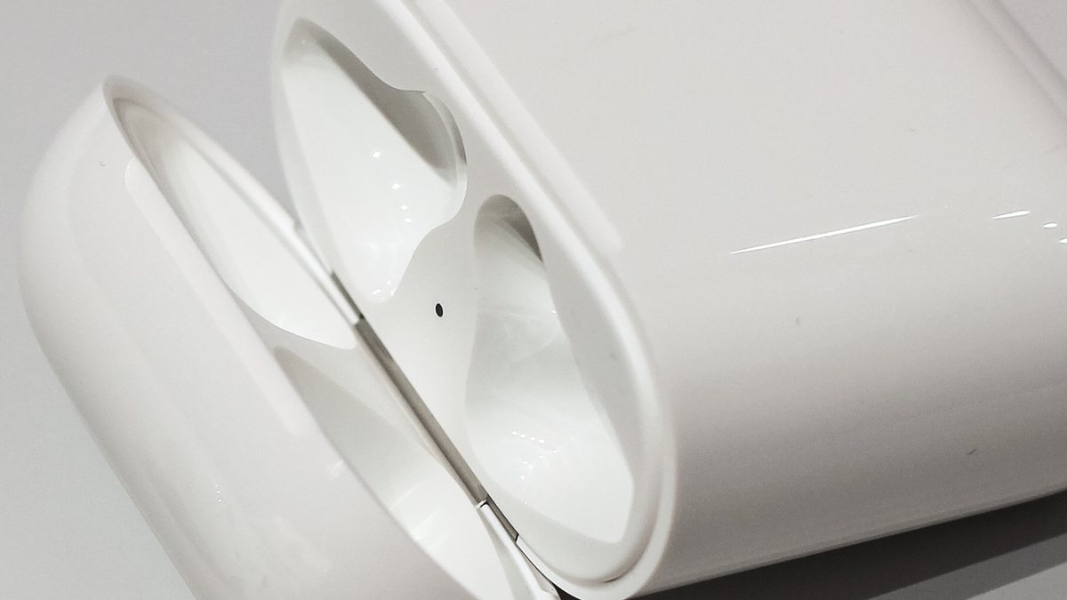 Close-up inside an AirPods charging case showing the two wells and the small metal charging contacts that can collect lint and grime