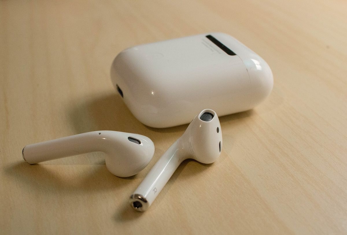 True wireless earbuds lying on a desk beside their charging case