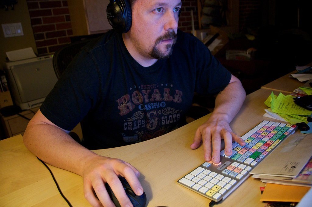 Man working at a desk with a keyboard and mouse while wearing over-ear headphones