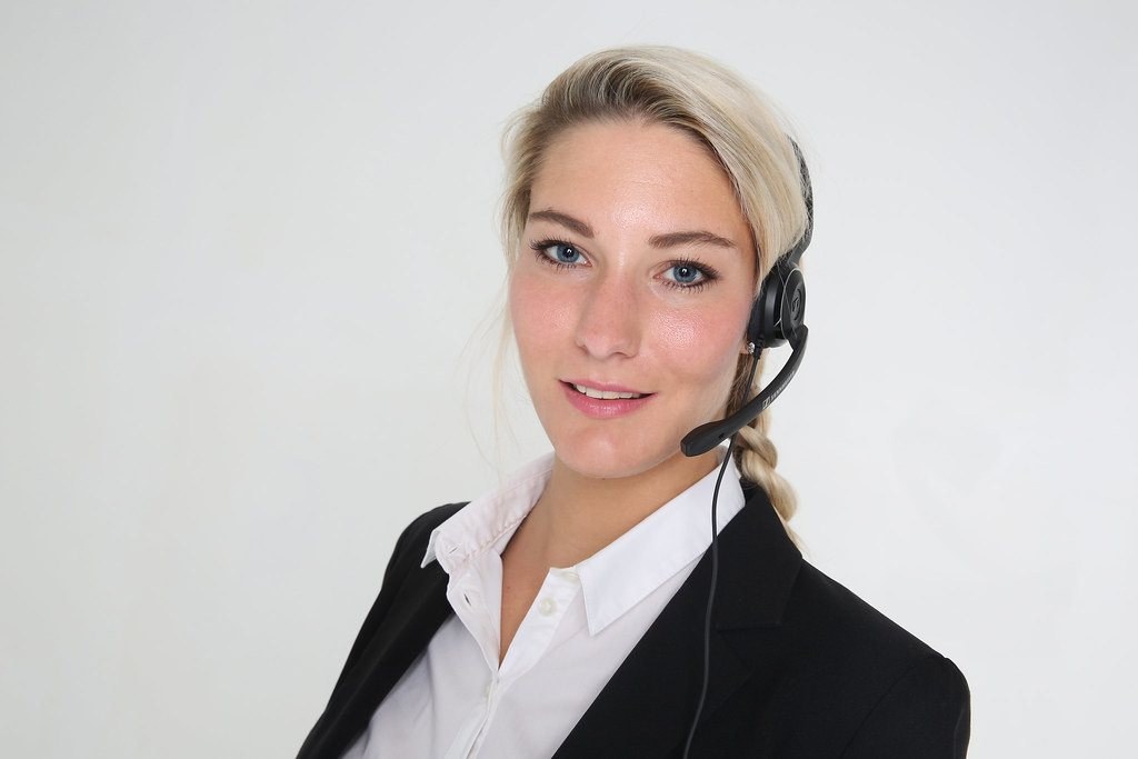 Office worker wearing a headset with a boom microphone in front of a plain background