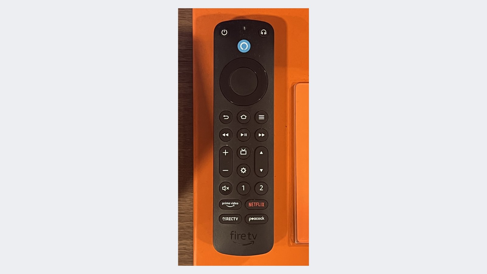 A real black Amazon Alexa Voice Remote Pro for Fire TV, showing its blue Alexa button, navigation ring, Back, Home and Menu buttons, and the volume, power and app shortcut rows