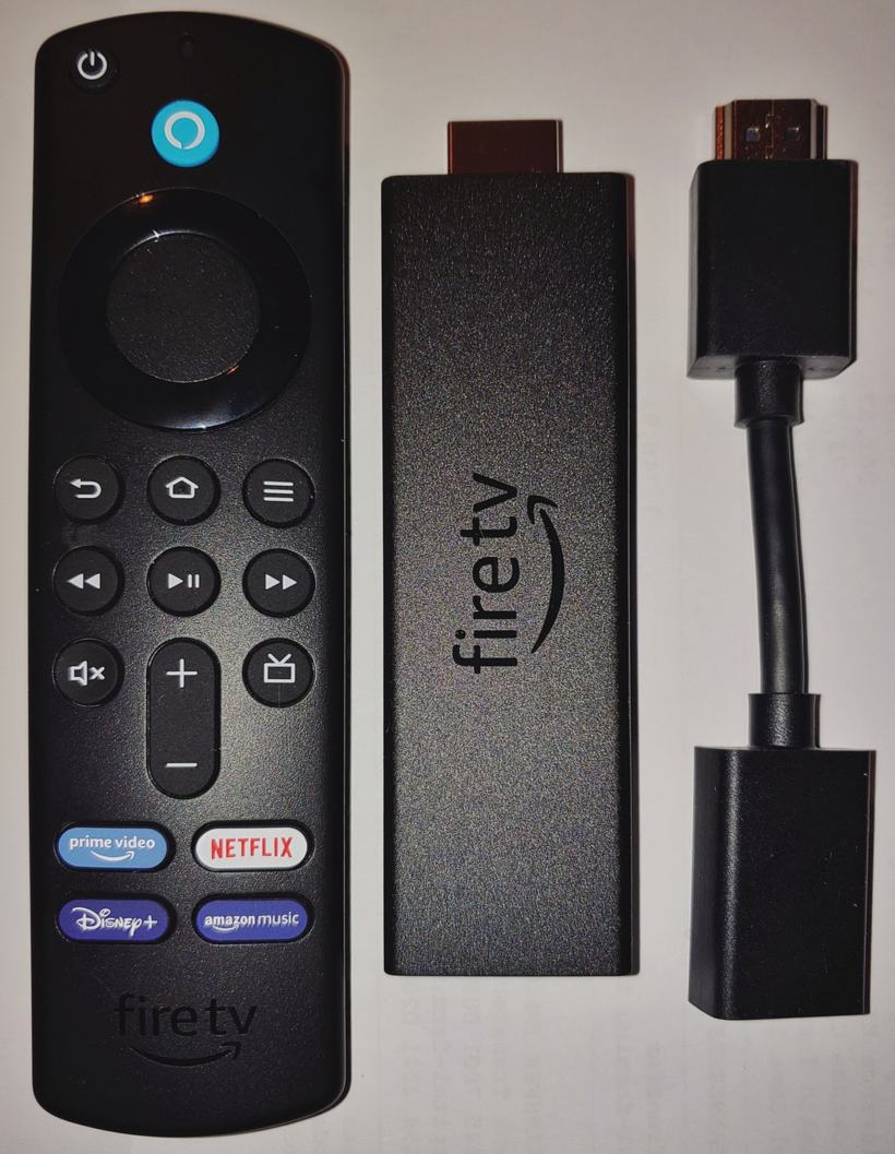 A Fire TV Stick 4K Max, its Alexa Voice Remote, and the short HDMI extender cable that ships in the box, laid side by side