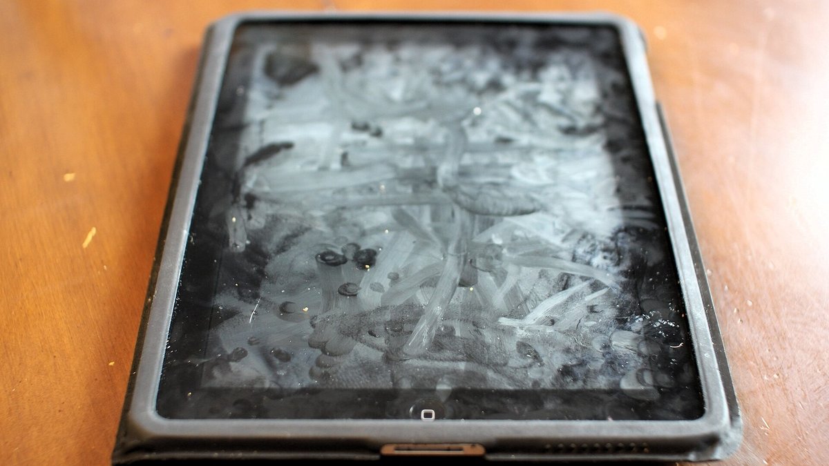 A tablet screen covered in heavy fingerprints and greasy smudges