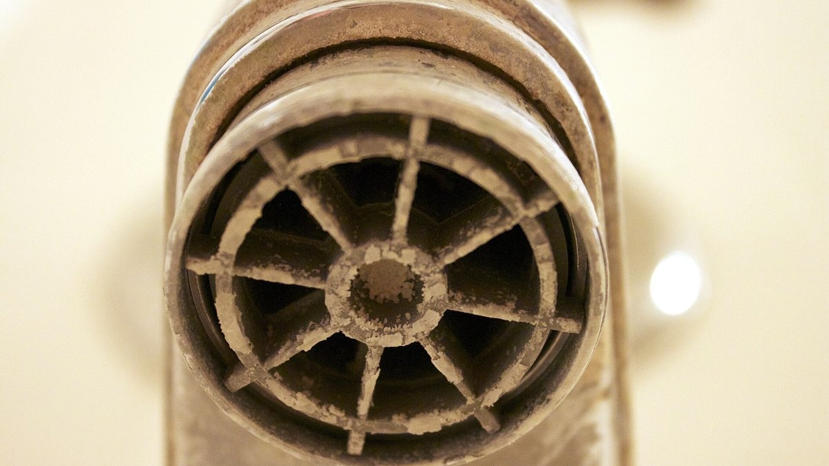 Heavy white limescale deposits built up on a chrome tap outlet