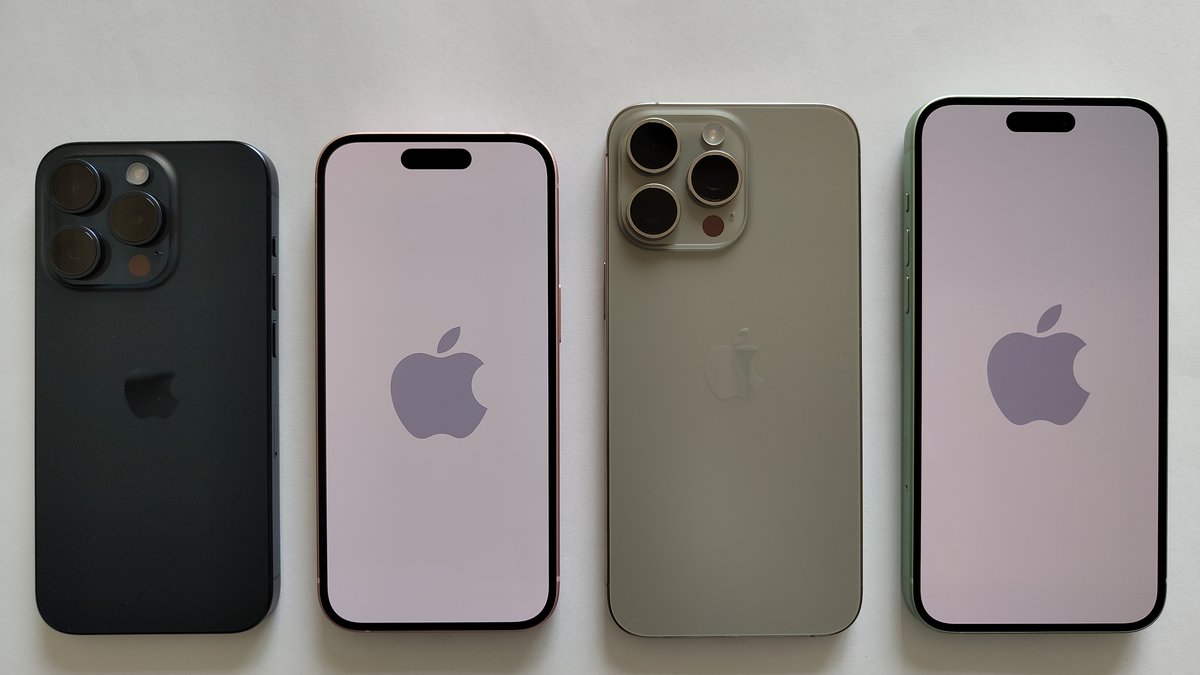 Four real iPhones laid side by side on a neutral surface, two showing the Apple logo on screen and two showing their rear camera systems