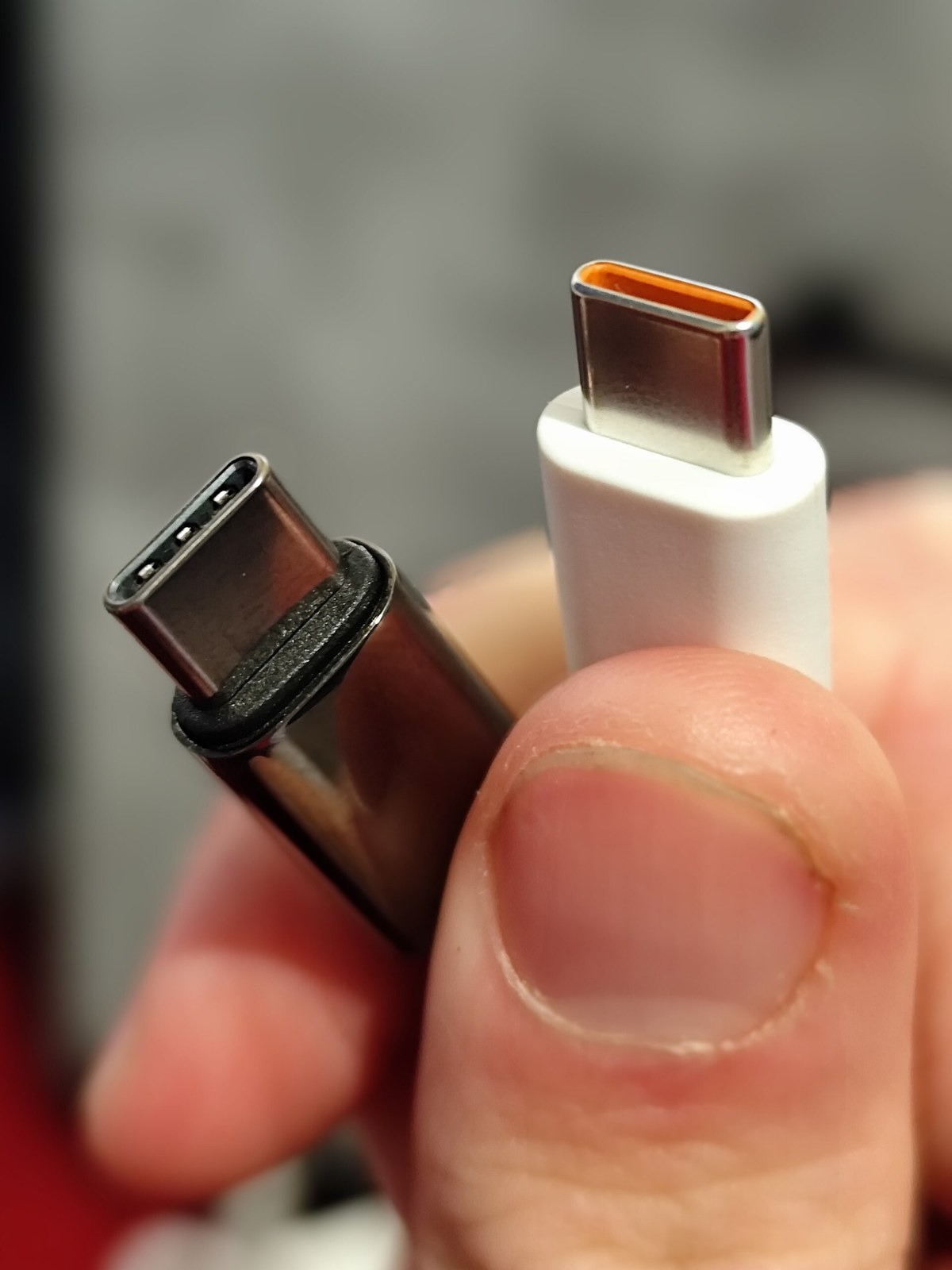 Close-up of two USB-C charging connectors held in a hand, showing the connector detail