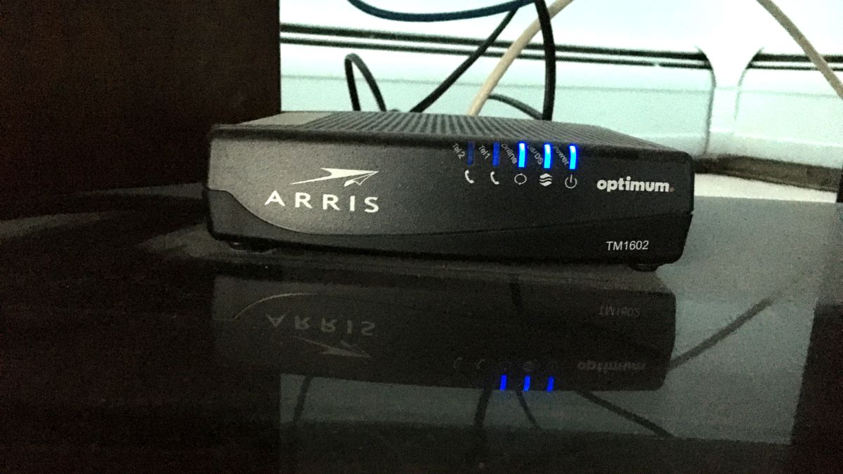 Front of an Arris TM1602 cable modem with its blue status lights lit, showing the power, upstream-downstream, and online indicators to check when wifi keeps dropping