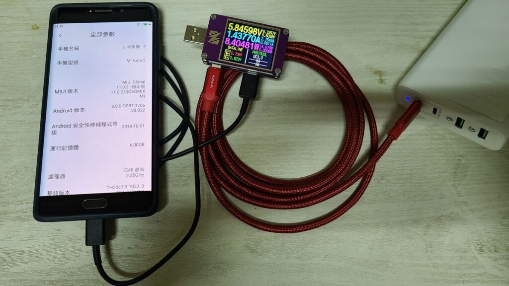 A real Xiaomi Mi Note 2 phone charging through a red braided USB cable and an inline USB power meter reading 5.85V, 1.44A and 8.4W, plugged into a white power bank