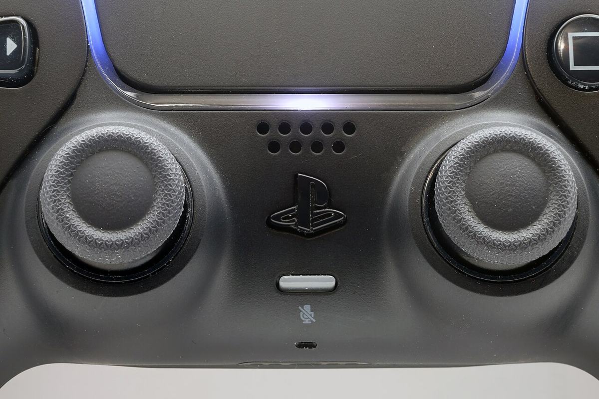 Close-up of a DualSense controller's twin analog sticks and PS button, the analog modules that wear out and cause stick drift