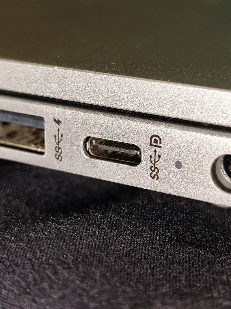 Close-up of a laptop USB-C port with a small DisplayPort D logo stamped beside it, the mark that means the port can output video over DisplayPort Alt Mode