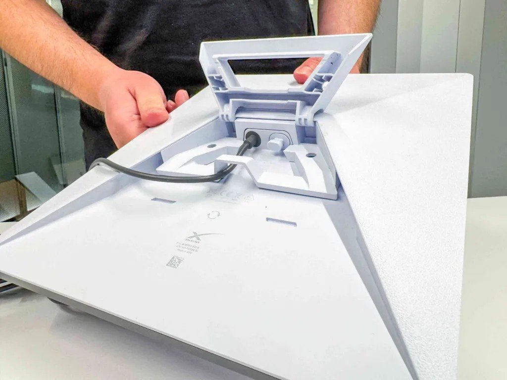 A hand holding the compact Starlink Mini dish, showing its single power cable and portable size