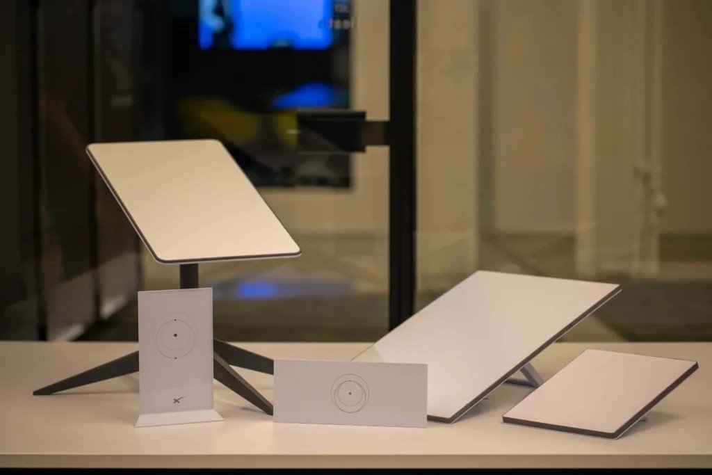 Real photo comparing Starlink dishes side by side: the Standard Actuated, Standard V4, and compact Starlink Mini dish showing the size difference